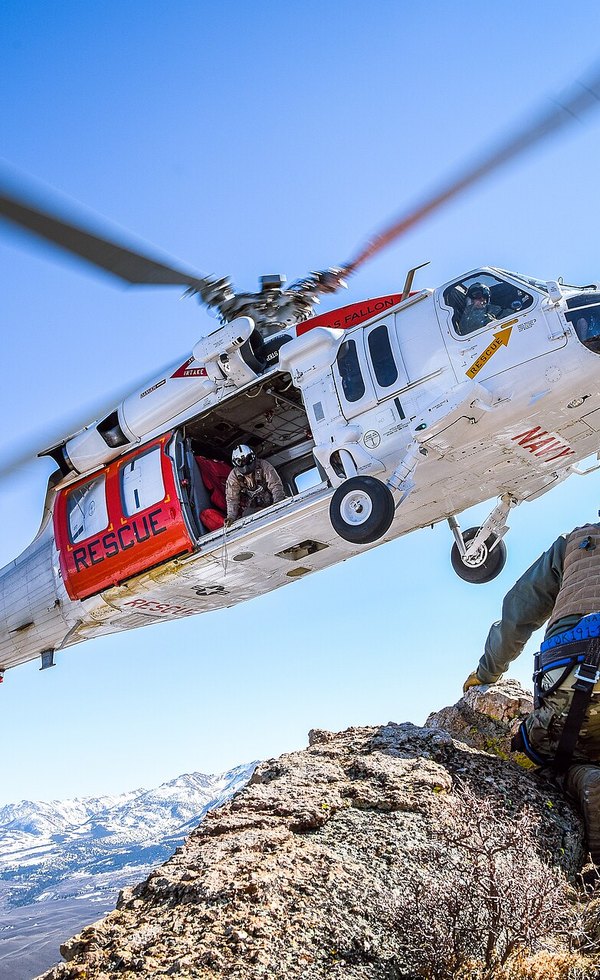 Rescue helicopter hovering over a mountain ridge during an extraction